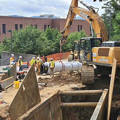 Construction workers install a pipe main on Hereford Drive.
