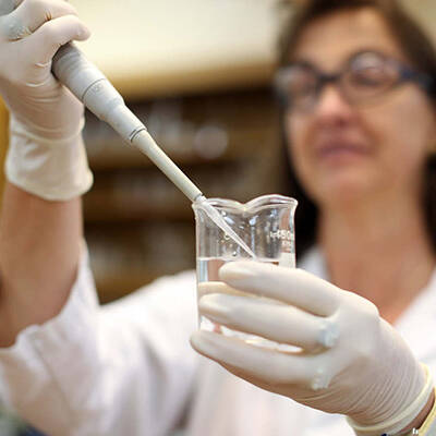 Chemist introduces reagents to a solution.